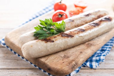 Ahşap masada domatesli ızgara sucuklu sosis.