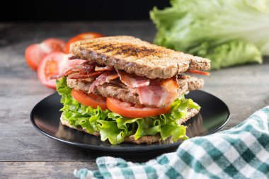 Bacon sandwich with lettuce and tomato on wooden table clipart