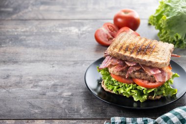 Bacon sandwich with lettuce and tomato on wooden table. Copy space clipart