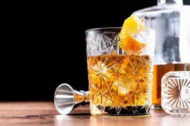 Old fashioned cocktail garnished with orange on wooden table clipart