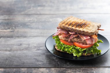 Bacon sandwich with lettuce and tomato on wooden table. Copy space clipart