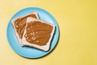 Sarı arka planda fıstık ezmeli tost. Üst Manzara. Boşluğu kopyala