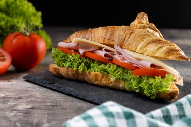 Tahta masada jambonlu, peynirli ve sebzeli kruvasan.