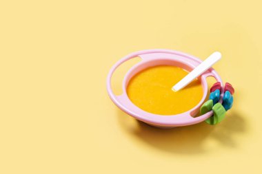 Bebek mamasıyla bovling. Sarı arka planda sebze püresi. Boşluğu kopyala