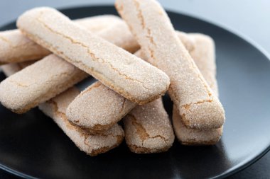 İtalyan bisküvileri kadın parmakları siyah arkaplan üzerinde savoiardi