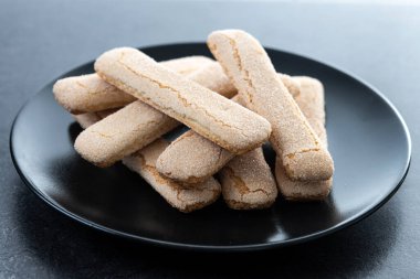 İtalyan bisküvileri kadın parmakları siyah arkaplan üzerinde savoiardi