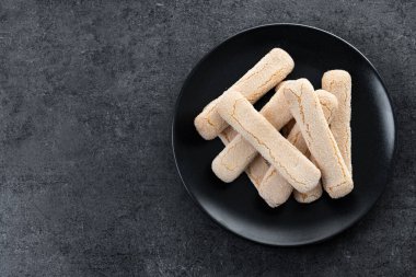 İtalyan bisküvileri kadın parmakları siyah arka planda savoiardi. Üst Manzara. Boşluğu kopyala