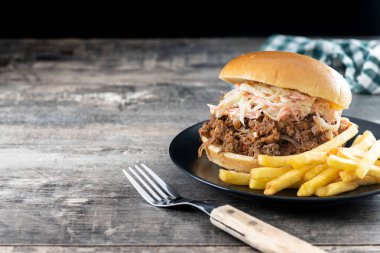 Lahana salatalı domuz sandviçi ve ahşap masada patates kızartması. Boşluğu kopyala