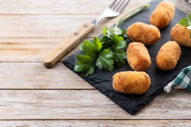 Tahta masada kızarmış morina kroketleri. Boşluğu kopyala