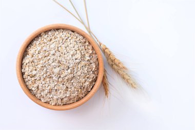 Rolled oats, healthy breakfast cereal oat flakes in bowl isolated on white background. Top view. Copy space clipart