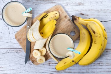 Beyaz ahşap masada taze muz suyu.