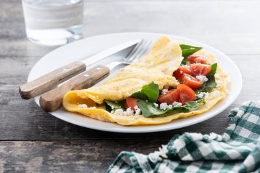 Domatesli omlet ve ahşap masada ıspanak.