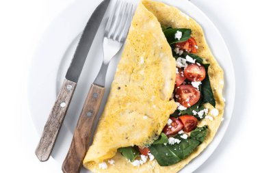 Beyaz arka planda domatesli ve ıspanaklı omlet.