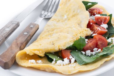 Beyaz arka planda domatesli ve ıspanaklı omlet.