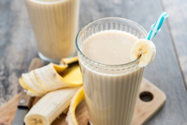 Tahta masada cam içinde taze ve sağlıklı muz suyu. Kapat.