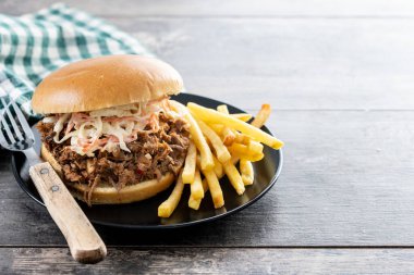 Lahana salatalı domuz sandviçi ve ahşap masada patates kızartması. Boşluğu kopyala