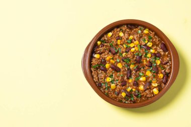 Geleneksel Meksika Chili con carne. Sarı arka planda domates soslu kıyma ve sebze güveci. Üst Manzara. Boşluğu kopyala