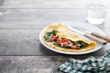 Domatesli omlet ve ahşap masada ıspanak. Boşluğu kopyala
