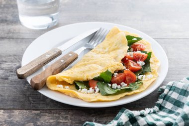 Domatesli omlet ve ahşap masada ıspanak.