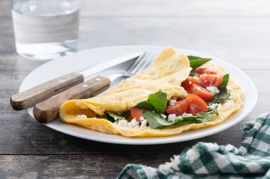 Domatesli omlet ve ahşap masada ıspanak.