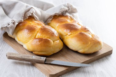 Geleneksel Paskalya örülmüş ekmek. Beyaz ahşap masada Tsoureki örgüsü