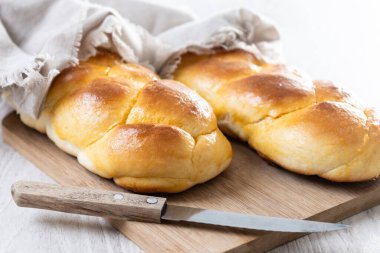 Geleneksel Paskalya örülmüş ekmek. Beyaz ahşap masada Tsoureki örgüsü