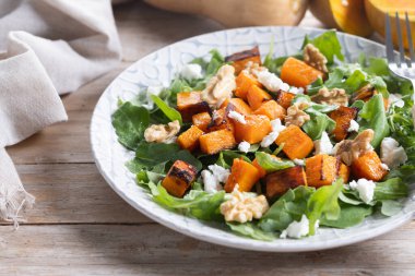 Kabak salatası, roka, ceviz ve ahşap masada beyaz peynir.