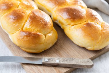 Geleneksel Paskalya örülmüş ekmek. Beyaz ahşap masada Tsoureki örgüsü