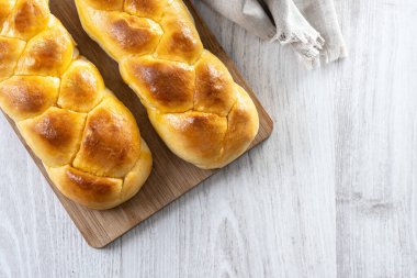Geleneksel Paskalya örülmüş ekmek. Beyaz ahşap masada Tsoureki örgüsü