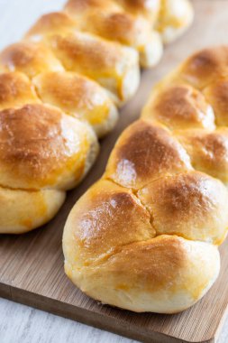 Geleneksel Paskalya örülmüş ekmek. Beyaz ahşap masada Tsoureki örgüsü