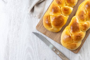 Geleneksel Paskalya örülmüş ekmek. Beyaz ahşap masada Tsoureki örgüsü