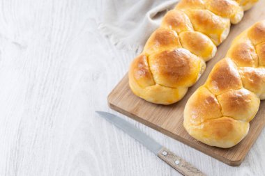 Geleneksel Paskalya örülmüş ekmek. Beyaz ahşap masada Tsoureki örgüsü