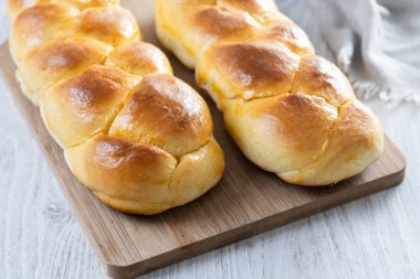 Geleneksel Paskalya örülmüş ekmek. Beyaz ahşap masada Tsoureki örgüsü