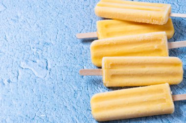 Mavi arka planda sarı buzlu şeker. Üst Manzara. Boşluğu kopyala