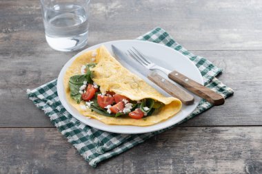 Domatesli omlet ve ahşap masada ıspanak.