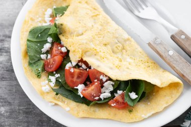 Domatesli omlet ve ahşap masada ıspanak.