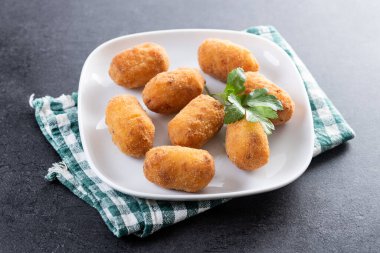 Siyah yüzeyde kızarmış morina kroketleri.