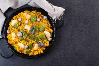 Tavşan, tavuk, garrofon fasulyesi, salyangoz, Fas yeşil fasulyesi ve siyah arka planda safranlı geleneksel Valensiyalı paella. Üst Manzara. Boşluğu kopyala