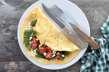 Domatesli omlet ve ahşap masada ıspanak.