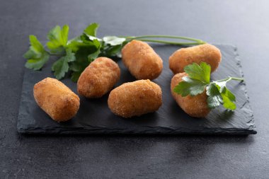 Siyah arkaplanda kızarmış morina kroketleri