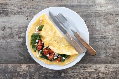 Domatesli omlet ve ahşap masada ıspanak.
