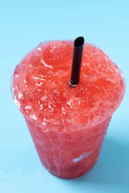 Kırmızı çilekli buzlu içecek mavi arka planda izole edilmiş. Soğuk yaz içeceği