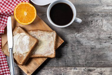Tahta masada kahvaltı için tereyağlı taze ekmek ve kahve.