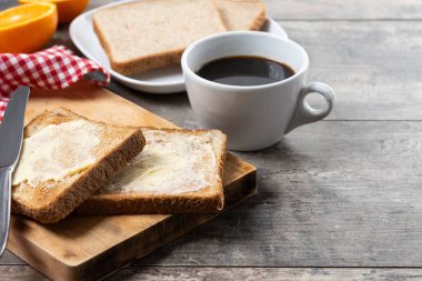 Tahta masada kahvaltı için tereyağlı taze ekmek ve kahve.