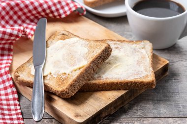 Tahta masada kahvaltı için tereyağlı taze ekmek ve kahve.