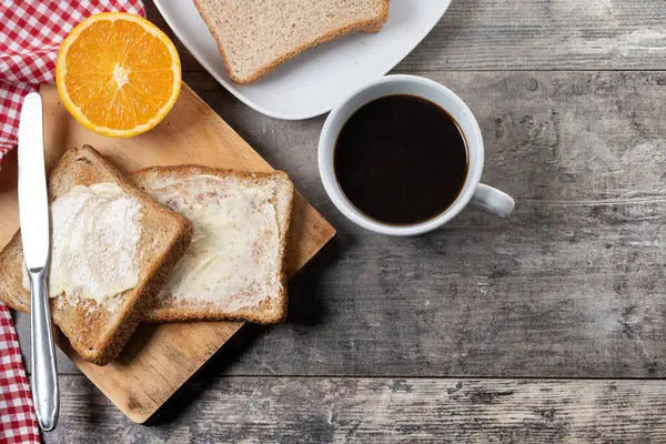 Tahta masada kahvaltı için tereyağlı taze ekmek ve kahve.