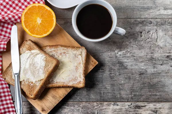 Tahta masada kahvaltı için tereyağlı taze ekmek ve kahve.