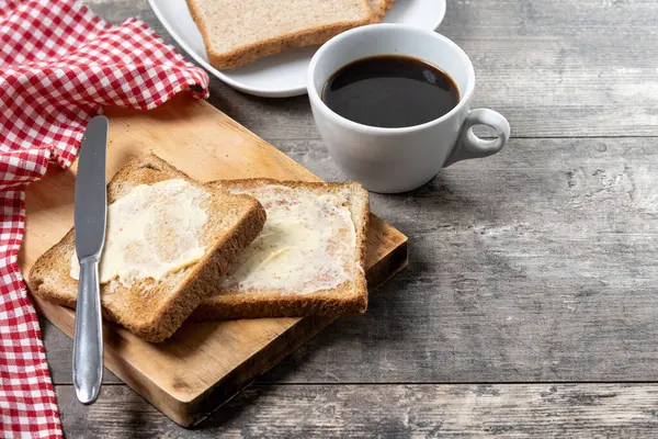 Tahta masada kahvaltı için tereyağlı taze ekmek ve kahve.
