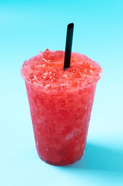 Kırmızı çilekli buzlu içecek mavi arka planda izole edilmiş.