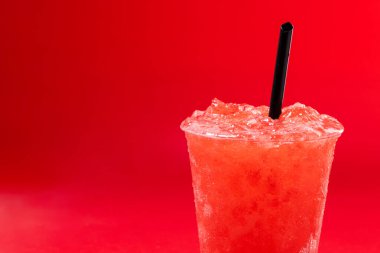 Kırmızı arka planda izole edilmiş kırmızı çilekli buzlu içecek.